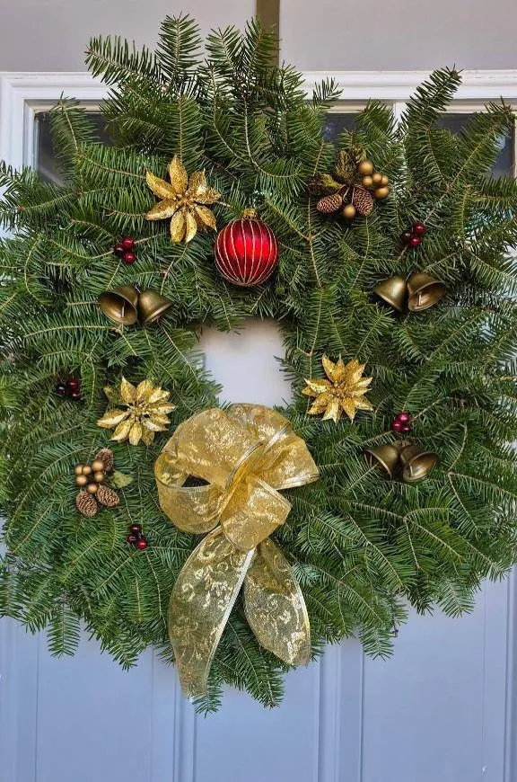 Balsam wreath with a gold bow, gold poinsettias, bells and a red ornament